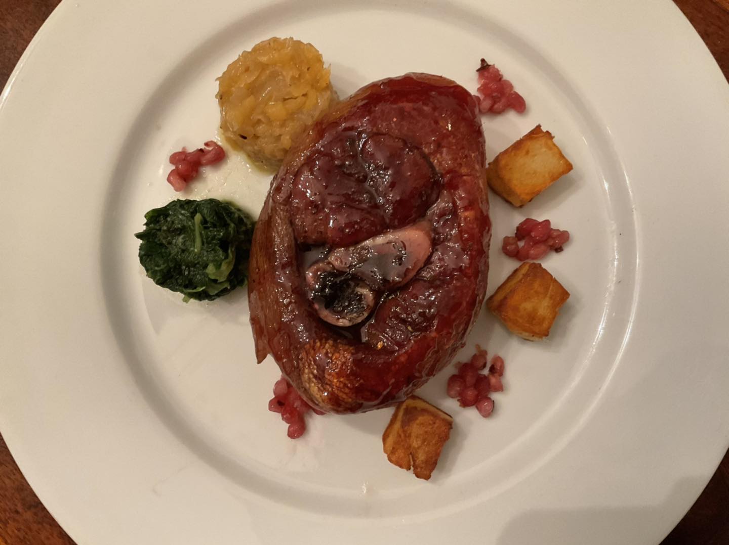 Slow-cooked Tuscan pork shank with pomegranate glaze and greens